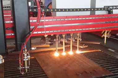 Multiple flame cutting heads in action on metal plate
